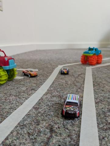 tiny cars driving along a road made of tape