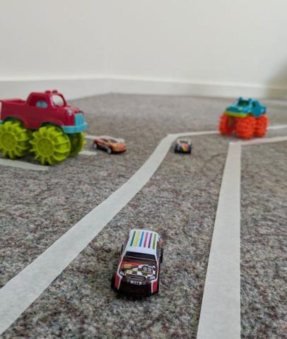 tiny cars driving along a road made of tape