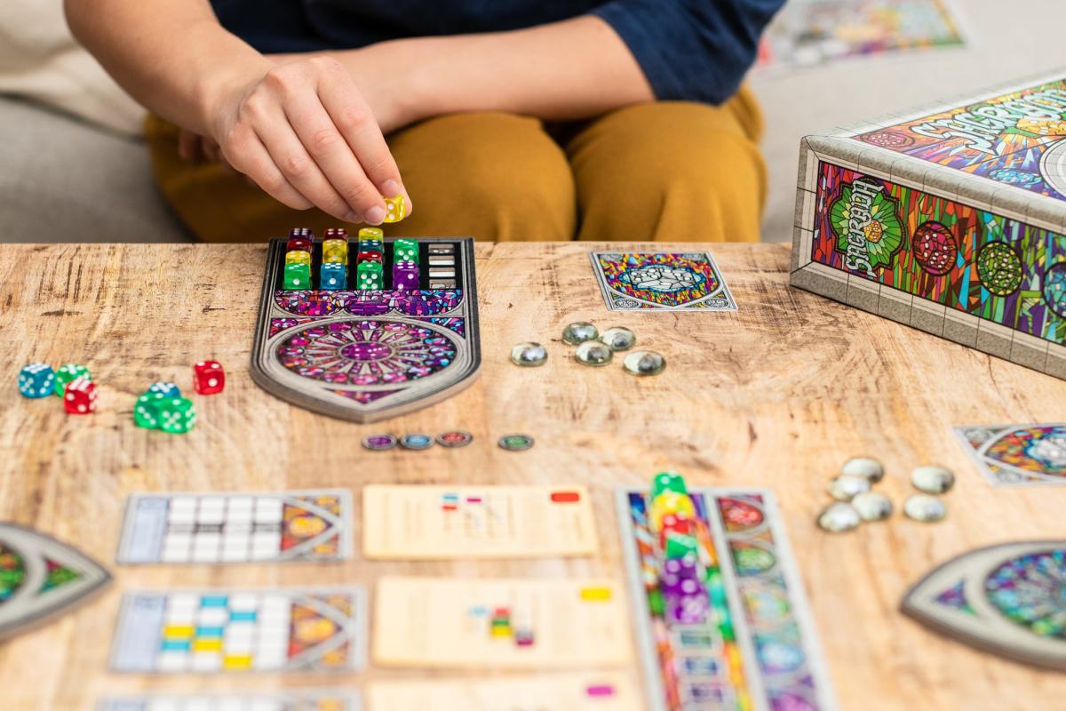 photo of hands moving board game piece over tiles