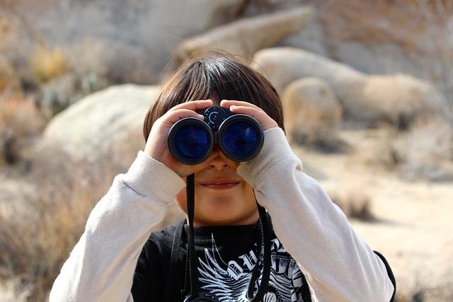 A boy looking through a pair of binoculars. 