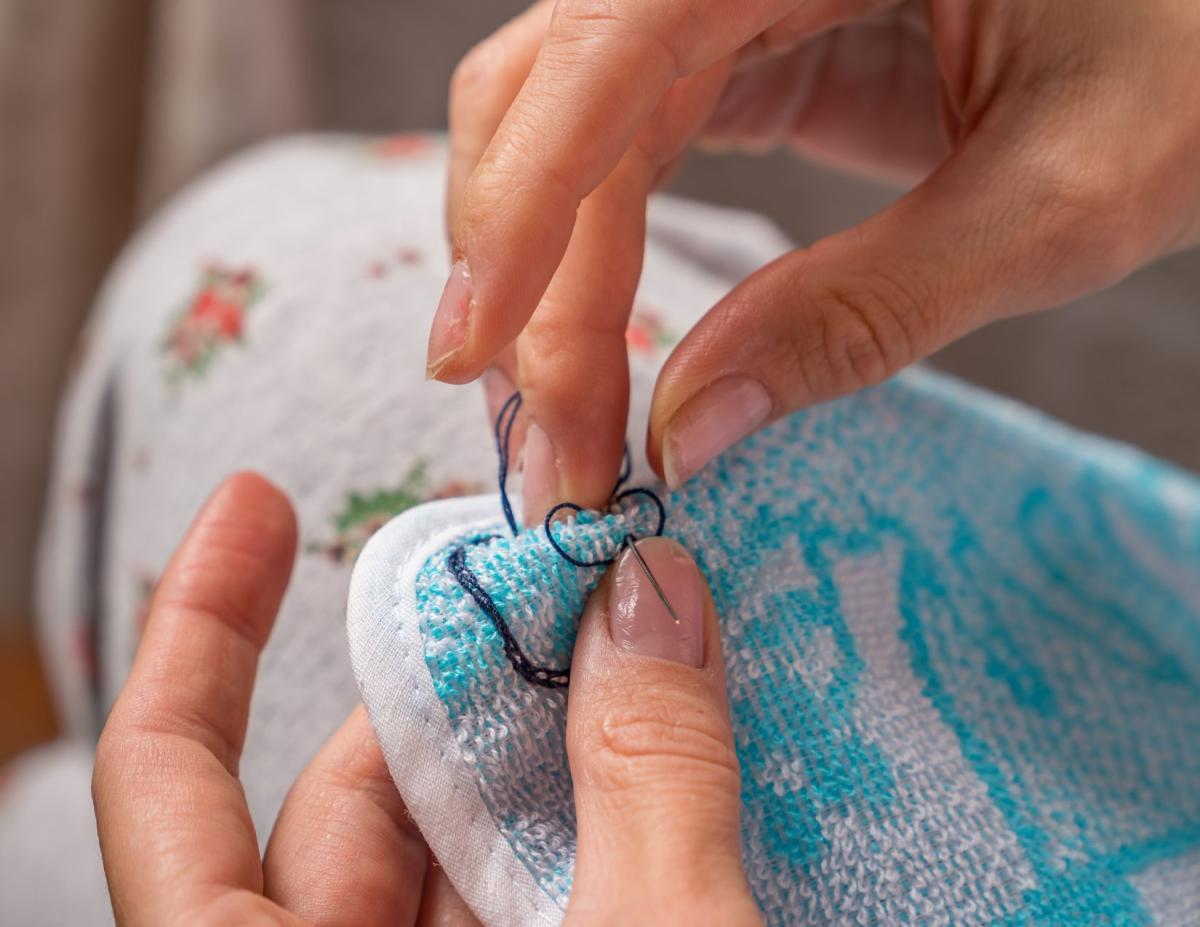 hands with needle and thread and a towel