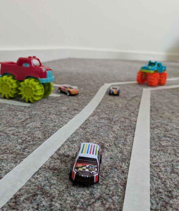 tiny cars driving along a road made of tape